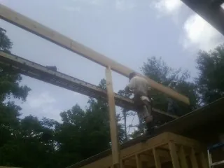 Carpenter setting a ridge beam over a new addition frame — Ice Dam Removal by Roofing Brothers in Ferguson