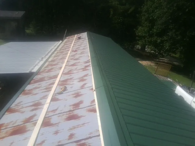Old rusted panels beside newly installed green metal roofing — Wind Damage Roof Repair by Roofing Brothers in Ferguson