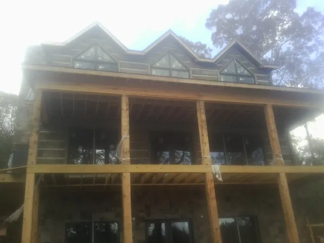 Dormers and porch framing on a large log home under construction — Roof Coating work by our crew in Ferguson