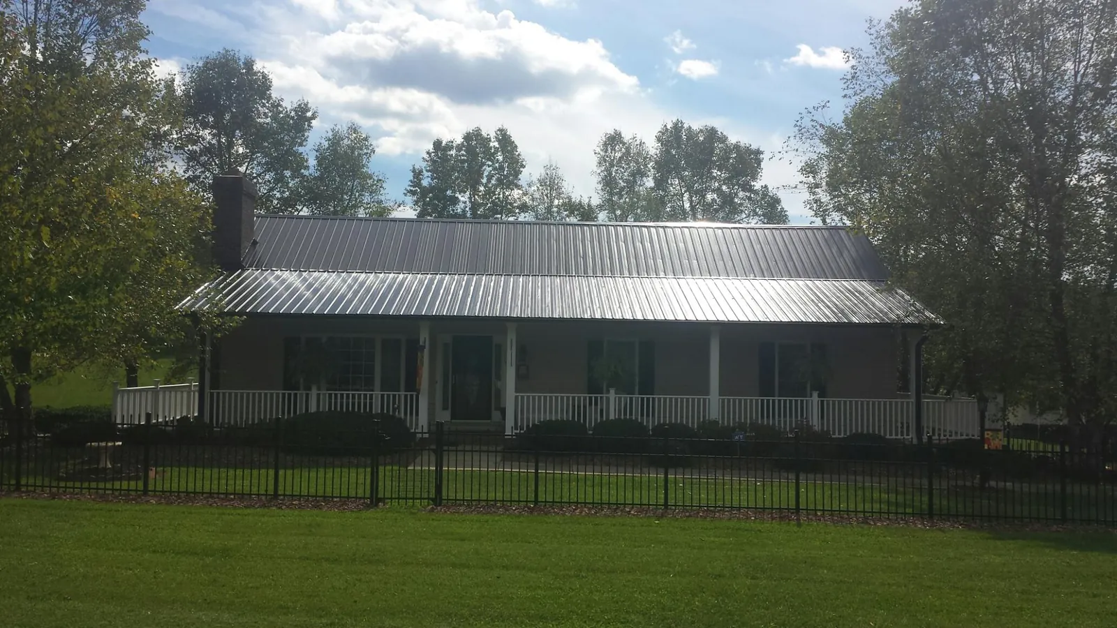 Gray metal roof on a brick ranch with a full width front porch — Gutter Guard Installation work by our crew in Ferguson