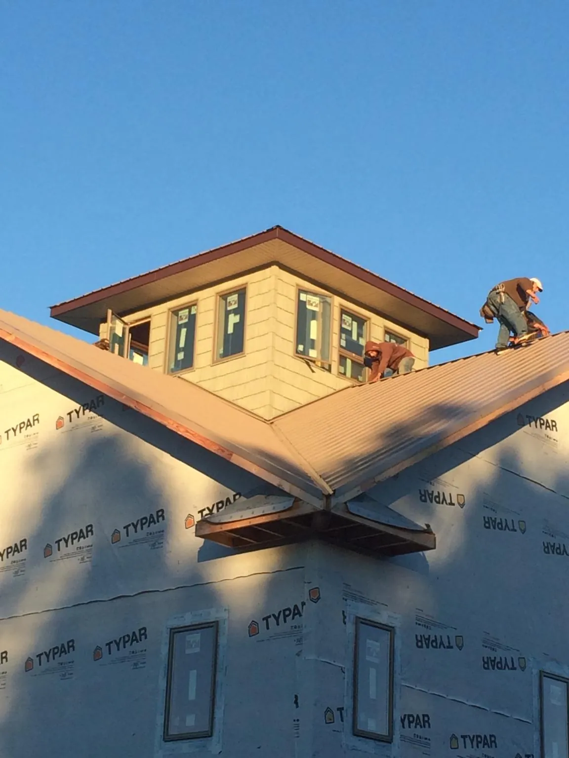 Roofers working around a rooftop cupola on a new metal roof at sunset — Roof Waterproofing in Ferguson by Roofing Brothers